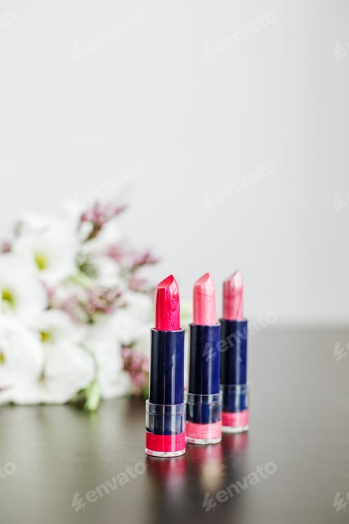 Preview: Set of colored lipsticks. Concept of cosmetics and care. Beautiful flowers. Copy space.