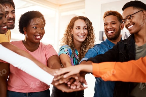 Preview: Cropped shot of a group of young designers standing with their hands in a huddle in the office