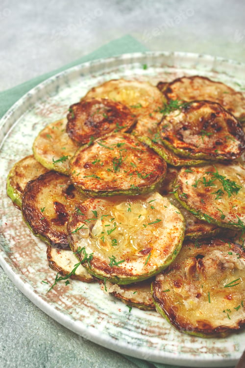 Preview: fried zucchini, cut into rings, with garlic and herbs, on a plate, top view, homemade, no people,