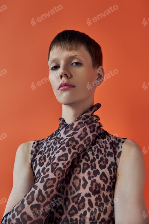 Preview: queer fashion concept, young man posing on orange backdrop, sleeveless animal print, leopard print