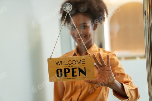 Preview: Woman hanging open sign on door.