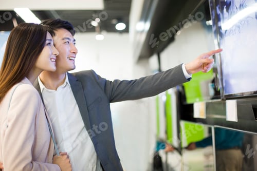 Preview: Young couple buying television in electronics store