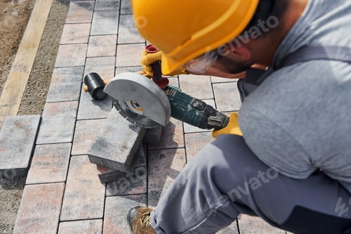 Preview: Close up view. Male worker in yellow colored uniform have job with pavement