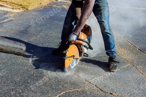 Preview: Using diamond blade saw machine, a construction worker cuts asphalt parking