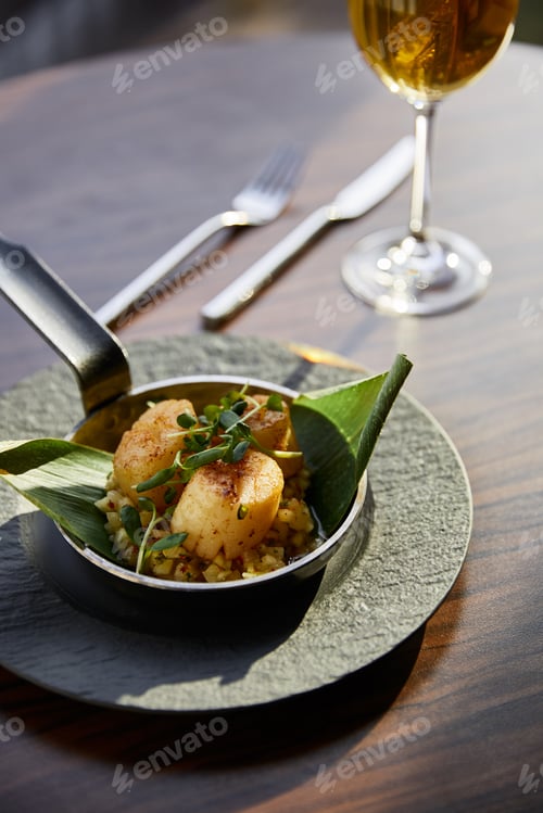 Preview: selective focus of delicious grilled scallops served in pan with microgreens near white wine in