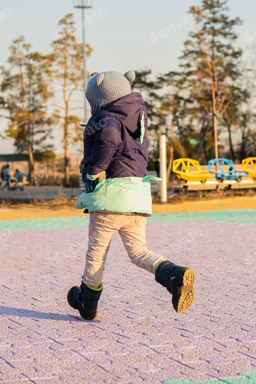 Preview: Portrait of a little funny child from behind running on the road in the city park at sunset
