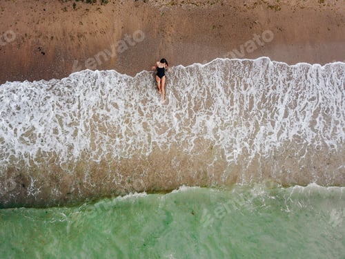 Vorschau: Junge asiatische Frau am Strand im Sand in der Nähe der Wellen