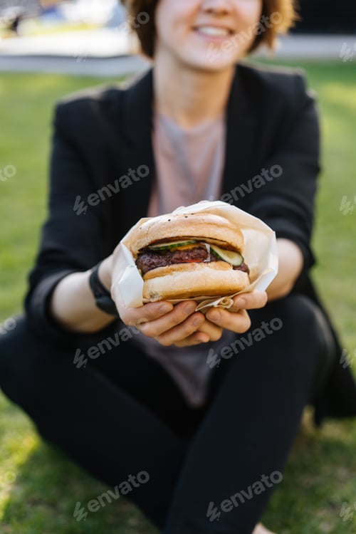 Preview: Girl enjoying takeaway burger in park