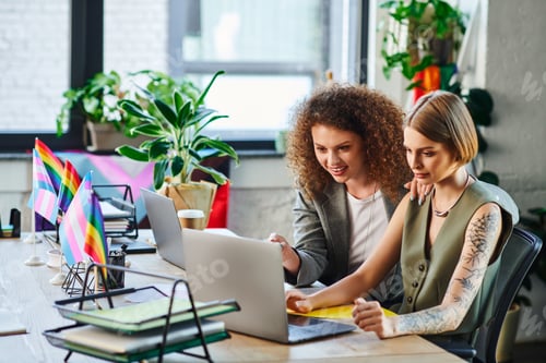 Preview: Engaging coworkers collaborate in a vibrant office workspace surrounded by plants and rainbow flags