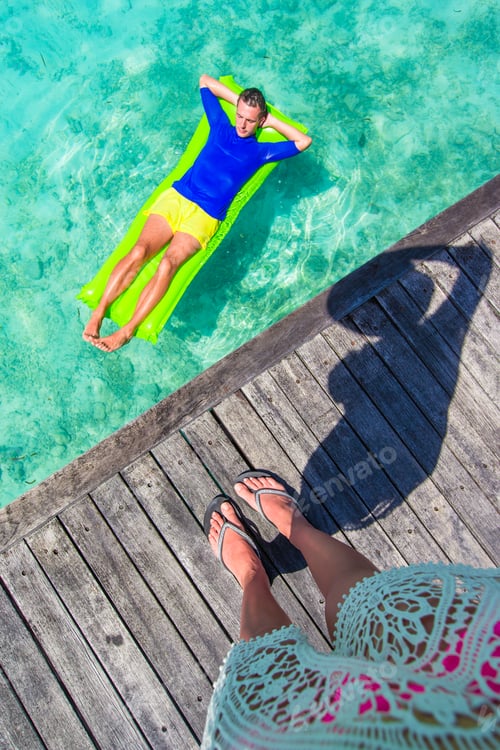 Preview: Young happy man relaxing on inflatable mattress in the sea