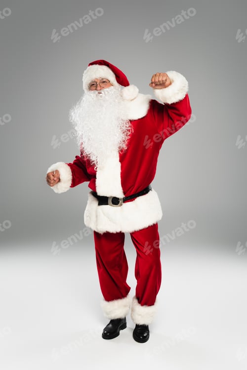 Preview: Full length of barded santa claus dancing and looking at camera on grey background