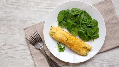 Preview: Homemade French Omelette with Fresh Herbs and Greens on a plate, top view. Flat lay, overhead