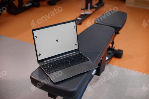 Preview: Laptop Displaying Blank Screen Resting on Gym Bench in Fitness Center