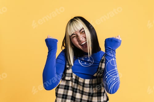 Preview: Asian girl with piercing screaming while making winner gesture