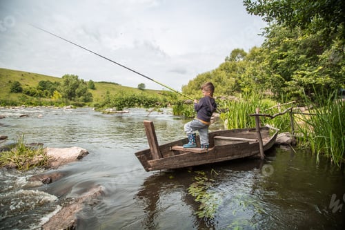 Preview: Boy with fishing rod fishing in a wooden boat