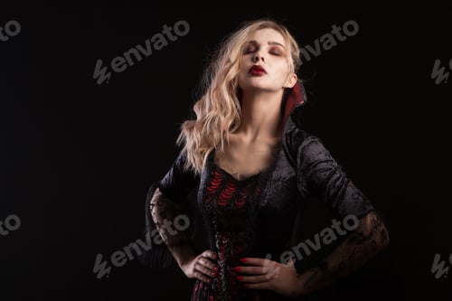 Preview: Woman dressed up like a vampire posing for halloween carnival on dark background