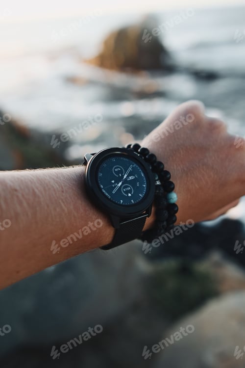 Preview: Close-up of a modern sports watch on the wrist of a man against a beach backdrop