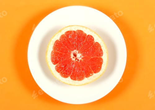 Preview: Fresh Grapefruit Lying On A White Plate That Stands On An Orange Background