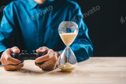 Preview: Gamer holds joystick control playing video game, glass hourglass timer showing sand flowing,