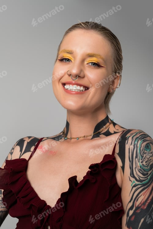 Preview: Stylish young woman with vibrant makeup and tattoos showcasing her unique fashion sense