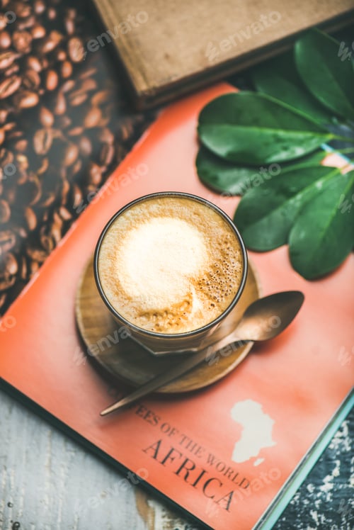 Preview: Cappuccino coffee in glass over table with bright magazine background