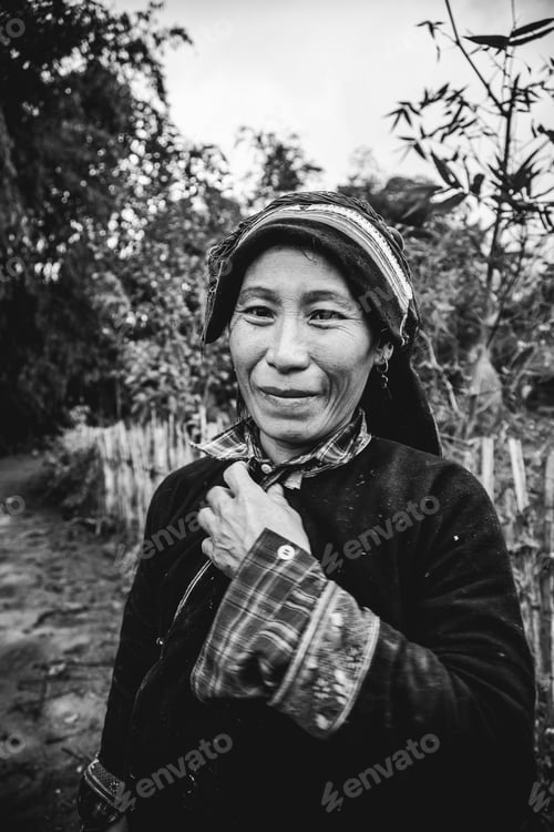 Preview: Smiling woman in cultural attire standing in a rustic outdoor setting