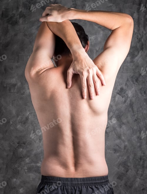 Preview: A man performing triceps stretch on grey background.
