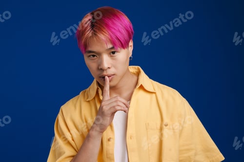 Preview: Asian boy with pink hair showing silence gesture at camera