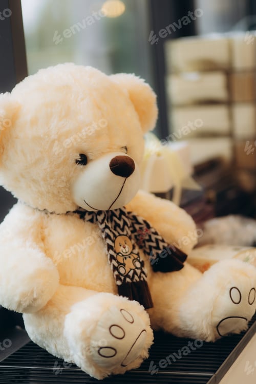 Preview: Close-Up of a Charming Teddy Bear With a Patterned Scarf Indoors