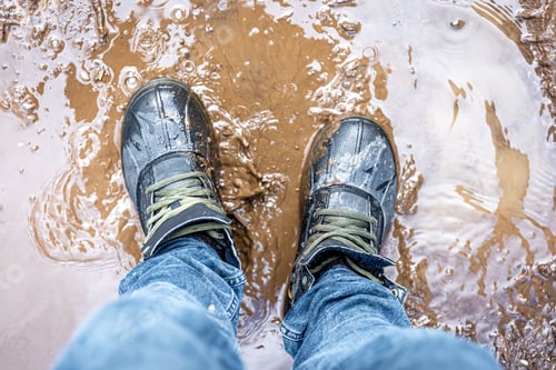 Preview: View from above on pair of trekking shoes in a mud.