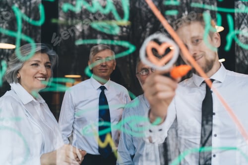 Preview: Happy colleagues taking notes on transparent board