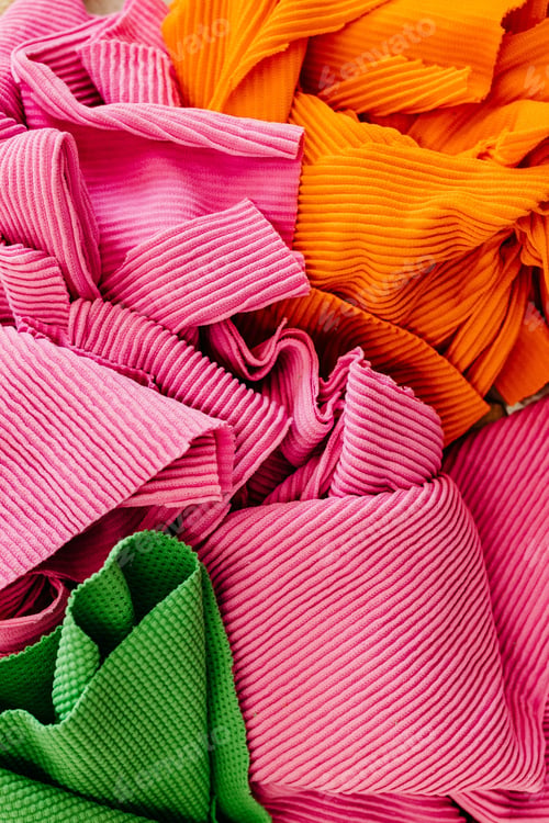 Preview: Closeup view of a pile of variously-colored fabrics