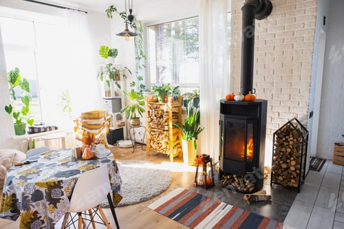 Preview: Bright sunny interior of the house with Black Metal Steel fireplace stove with fire and firewood wit
