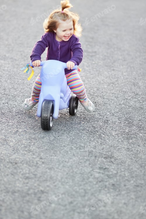 Preview: Having fun on her tricycle. A cute baby girl riding her tricycle outside on the street.