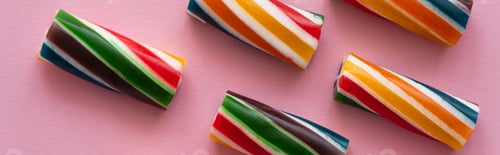 Preview: Top view of sweet striped candies on pink background, banner