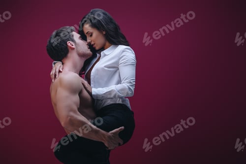 Preview: shirtless man holding on hands and kissing girl in white shirt on dark background