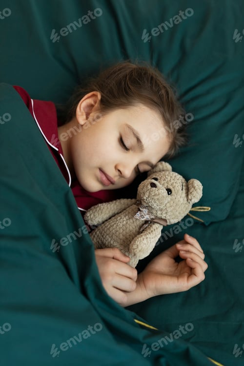 Preview: 6 year old girl in red pyjamas sleeps in a green bed with her teddy bear toy