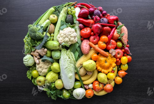 Preview: Various vegetables and fruits laid out in a circle on a dark background.