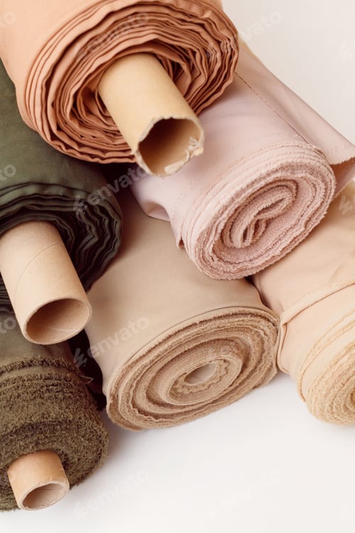 Preview: Stack of pastel color fabric rolls of synthetic and natural fabrics