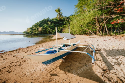 Preview: Bangka boat on sandy remote beach with golden sunset light. El Nido bay. Philippines