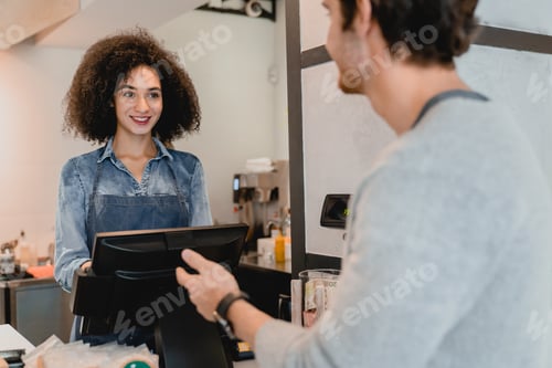 Preview: Cheerful african beautiful waitress servicing the customer at cafe counter