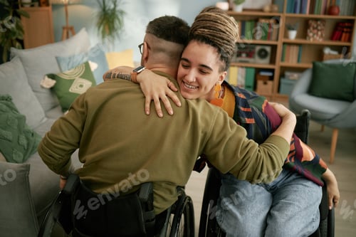 Preview: Young Man and Woman in Wheelchairs Hugging at Home