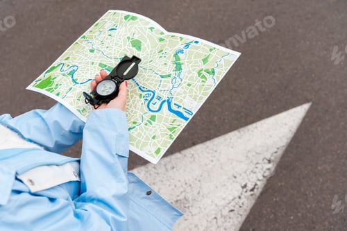 Preview: cropped view of woman holding map and compass on street