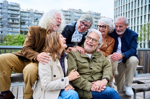 Preview: Group of six seniors grey hair joyful people having fun together sitting on bench in urban park.