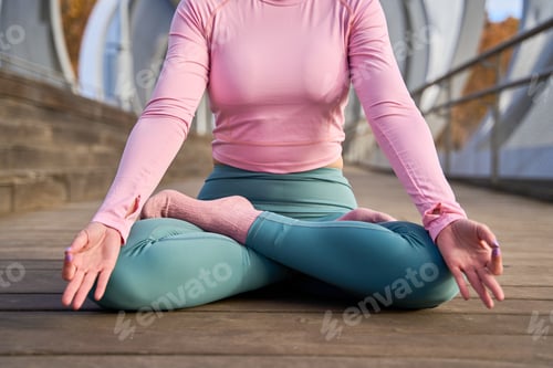 Preview: Woman practicing yoga meditation outdoors in lotus position