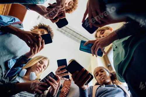 Preview: Below view of group of teenagers using smart phone at high school.