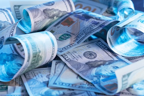 Preview: Piles of rolled and flat hundred dollar bills scattered on a table