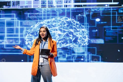 Preview: Jolly woman at event presents artificial intelligence using tablet and mic