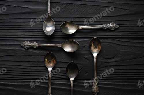 Preview: Directly above a shot of old spoons on a black table