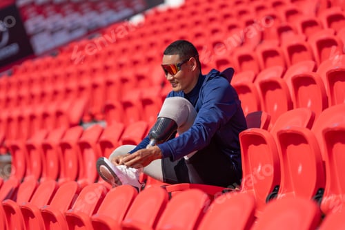 Preview: Asian para-athletes with prosthetic blades sprint on standing at stadium. seats in football stadium